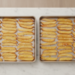 Zwei Backbleche mit gleichmäßig angeordneten Kartoffelwedges.