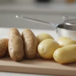 Kartoffeln auf Schneidebrett vor Küchenzubehör