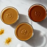 Drei Gläser Saucen auf Marmortisch mit Gewürzen.