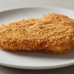 Knusprige panierte Fleischscheibe auf weißem Teller