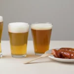 Drei Biergläser und Würstchen auf einem Teller
