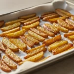 Gebackene Kartoffelwedges auf einem Backblech.